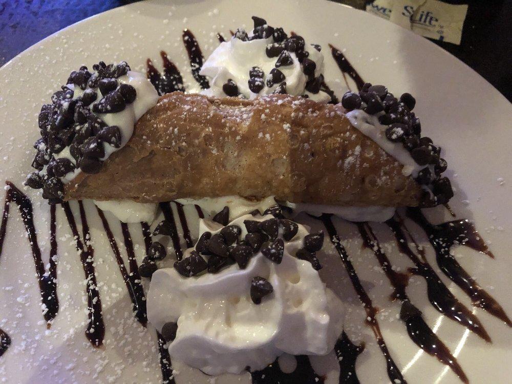 Cannoli · A crispy pastry shell filled with creamy ricotta and chocolate chips dusted with powdered sugar.