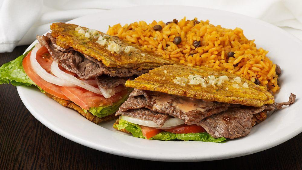 El Jibarito Sandwich · The famous Puerto Rican sandlwich made with your choice of grilled chicken, bistec or pork, in between 2 flattened fried green plantains, garlic flavored mayonnaise, lettuce, tomato, with a side of arroz con gandules (rice with pigeon peas and pork).