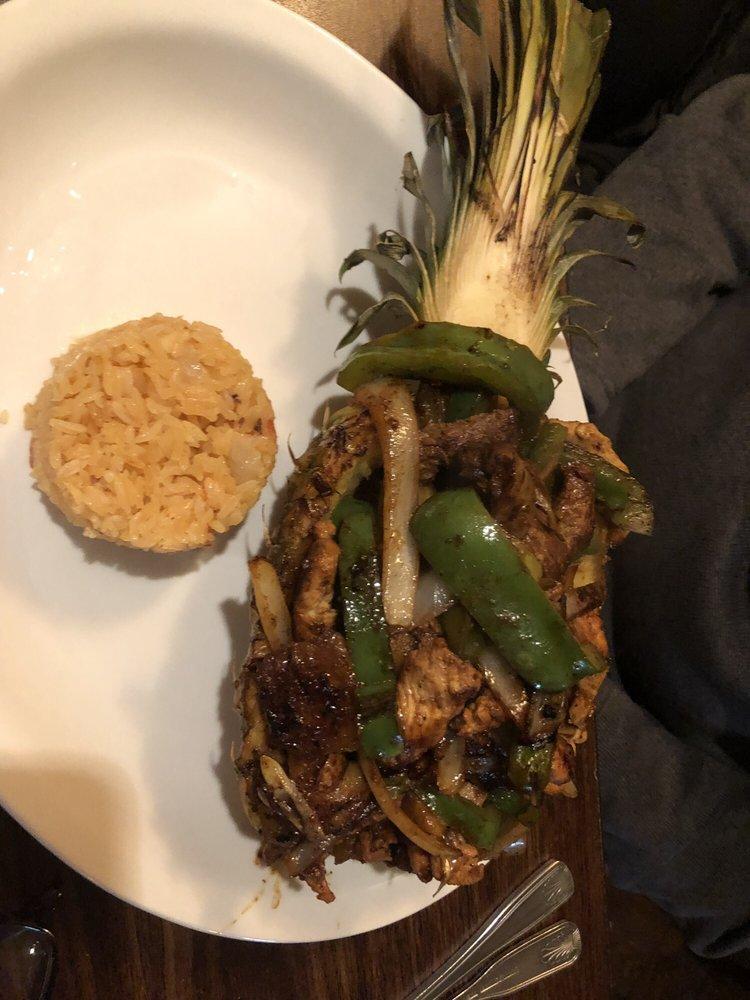 Pina Loca · Grilled pineapple stuffed with chicken, steak, peppers and onions in a al pastor sauce topped with melted cheese with a side of rice.