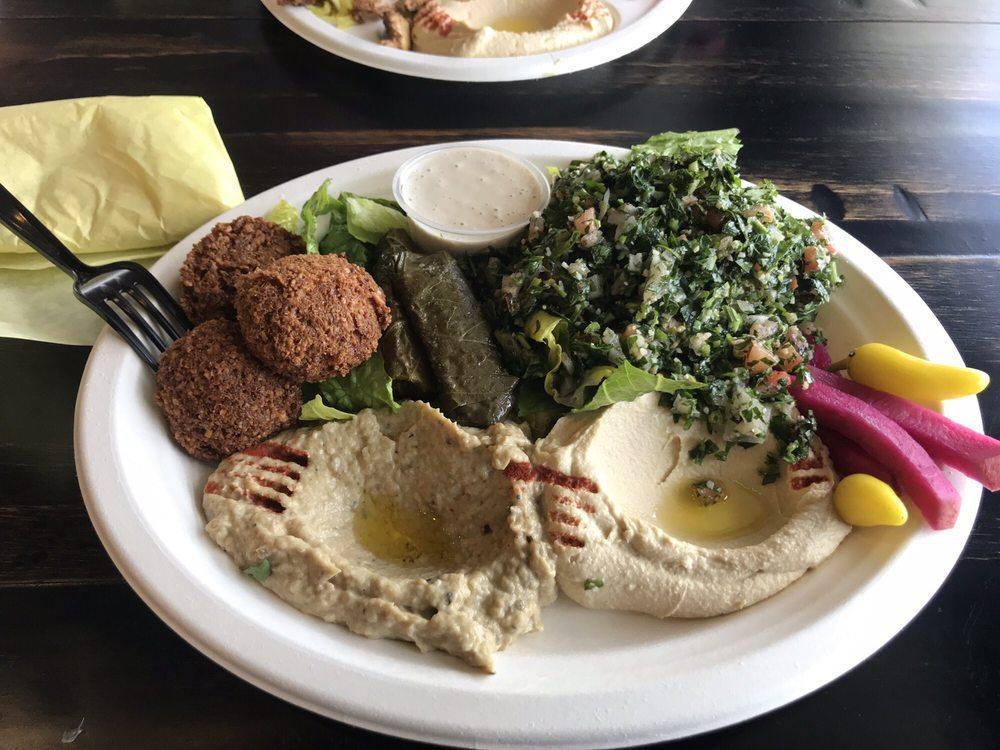 Vegetarian Plate · Hummus, baba ghanoush, tabbouleh, 2 pieces of falafel, 2 pieces of stuffed grape leaves (dolmas), and pickles served with pita bread, and tahini sauce. Vegan.