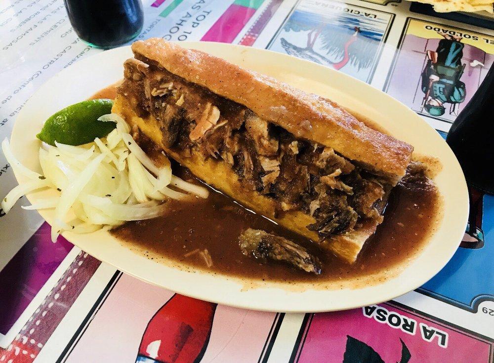 Torta Ahogada · The most popular sandwich in Guadalajara, Jalisco. Crispy sourdough bread with carnitas, beans, marinated onions, smothered in a tomato sauce and a spicy chili sauce to your taste.
