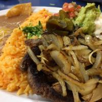 Bistec Encebollado · 8oz of flat grill steak topped with sautéed onions, served with rice, refried beans garnishe...