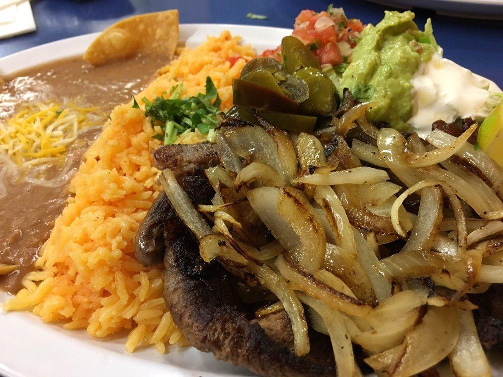 Bistec Encebollado · 8oz of flat grill steak topped with sautéed onions, served with rice, refried beans garnished with cheese and tortilla chips, lettuce, guacamole, sour cream, pico de gallo, jalapeño peppers, lime wedges and tortillas on the side