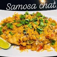 Samosa Chat · A homemade spicy pastry filled with herbs, potatoes and peas. Smothered with yogurt, mint an...