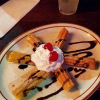 Churros · A unique dessert of fried flour sticks rolled in cinnamon and sugar, whipped cream on the si...