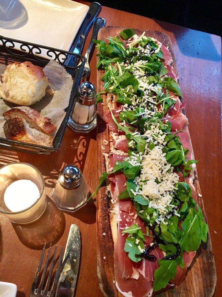 Prosciutto and Fig Flatbread · Prosciutto di Parma, goat cheese, fig jam, baby arugula and balsamic glaze.