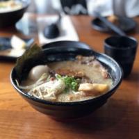 Tonkotsu Shoyu Ramen · Rich pork broth flavored with soy sauce and topped with black garlic oil. It comes paired wi...