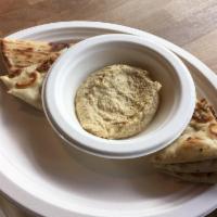 Hummus and Pita · Homemade hummus and grilled pita bread. Topped with our house spicy sauce.