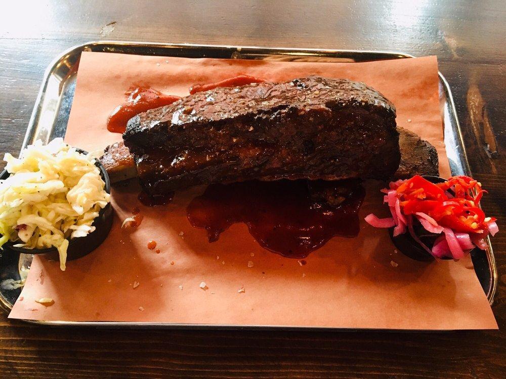 Brontosaurus Rib · On-the-bone, slow-smoked short rib with almost a full pound of meat on the rib. Served with an optional assortment of pickled veggies & slaw.