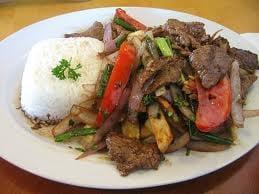 Lomo Saltado · Tender steak mixed with onions and tomatoes served over french fries and rice.
