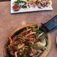 Fajita · Corn tortilla chips smothered in queso sauce, topped with grilled steak or chicken, onions, ...