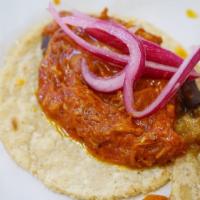 Cochinita Pibil · Shredded pork cooked in a sweet, red achiote spice atop black beans. Served with Yucatan com...