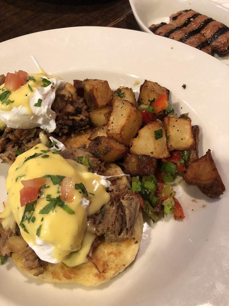 Cochon Eggs Benedict · Slow braised pork on a biscuit with 2 soft poached eggs, hollandaise and served with home fries.
