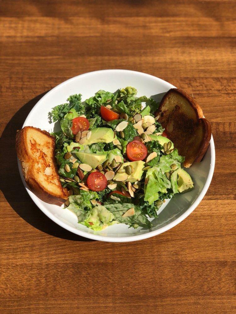 The Green Queen Salad · A blend of crisp kale and romaine, topped with chopped avocado, toasted almonds, pepitas and hemp seeds, tossed in a creamy lemon dijon dressing.  Vegan.