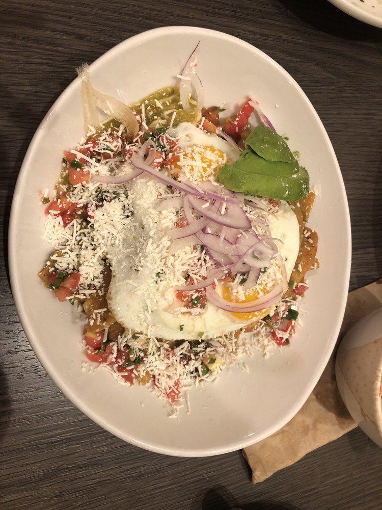 Chicken Chilaquiles · Housemade tortilla chips, avocado, cotija cheese, red onion, sour cream, tomatillo salsa, two sunny side eggs.