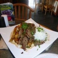 Lomo Saltado · Tender strips of steak, Roma tomatoes and red onions sauteed and served over french fries wi...