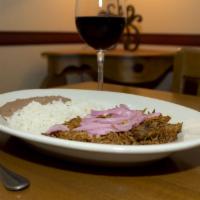 Cochinita Pibil · Shredded tender pork loin in a Yucatan-style pibil sauce topped with vinaigrette onions. Ser...