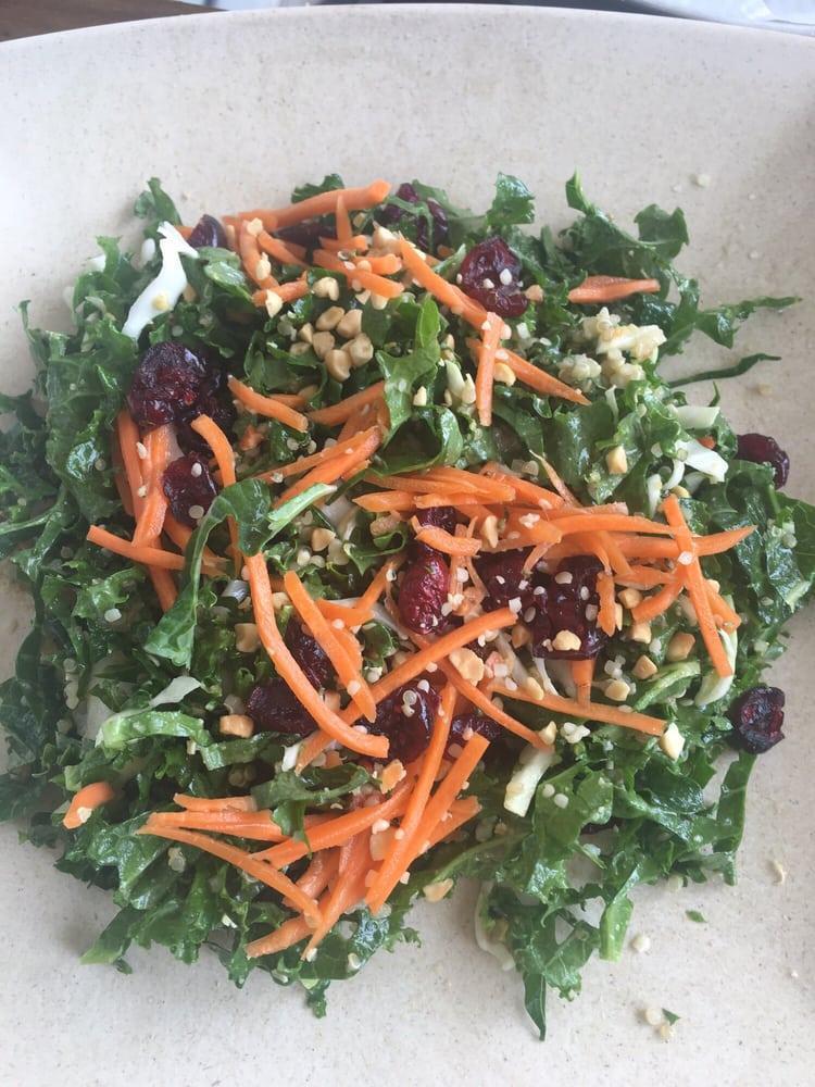 Kale Salad · Kale, cabbage, quinoa, serrano peppers, scallion mix, craisins, carrots, crushed peanuts, hemp seeds, and peanut dressing.