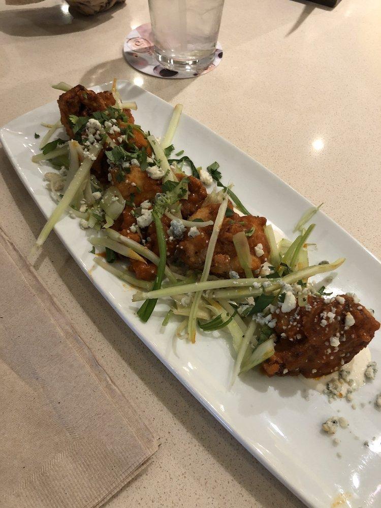 Spicy Buffalo Cauliflower · Fresh cauliflower florets buttermilk-battered and fried to a golden brown, then tossed in housemade Sriracha Buffalo sauce and topped with a salad of celery, cilantro, scallions and gorgonzola. Vegetarian.