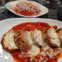 Eggplant Parmigiana · Breaded eggplant topped with our signature marinara and melted cheese, served with angel hai...