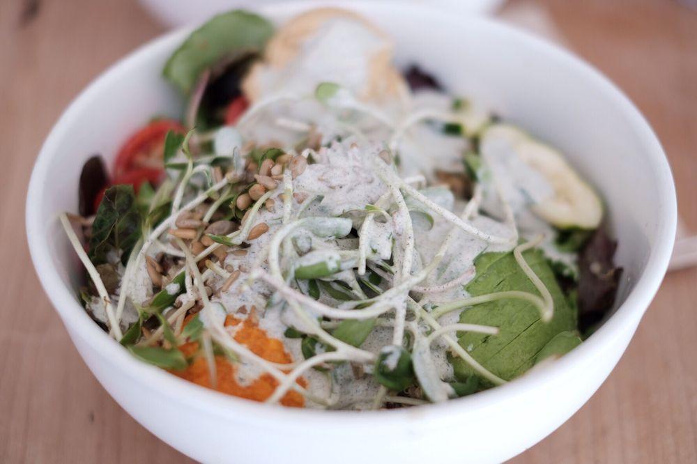 Nourish Bowl / Wrap · Quinoa, yams, avocado, sprouts, hummus, cucumber, mixed greens, tomatoes, beet sauerkraut, sunflower seeds. Oil- free creamy dill hemp dressing. Available as a grain bowl or in a raw spinach, gluten-free wrap.