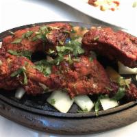 Tandoori Chicken · Chicken marinated in chef’s special spices. Baked in a special clay oven and served on a siz...