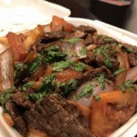 Lomo Saltado · Marinated tender steak sauteed with onions and tomatoes served over french fries and rice.