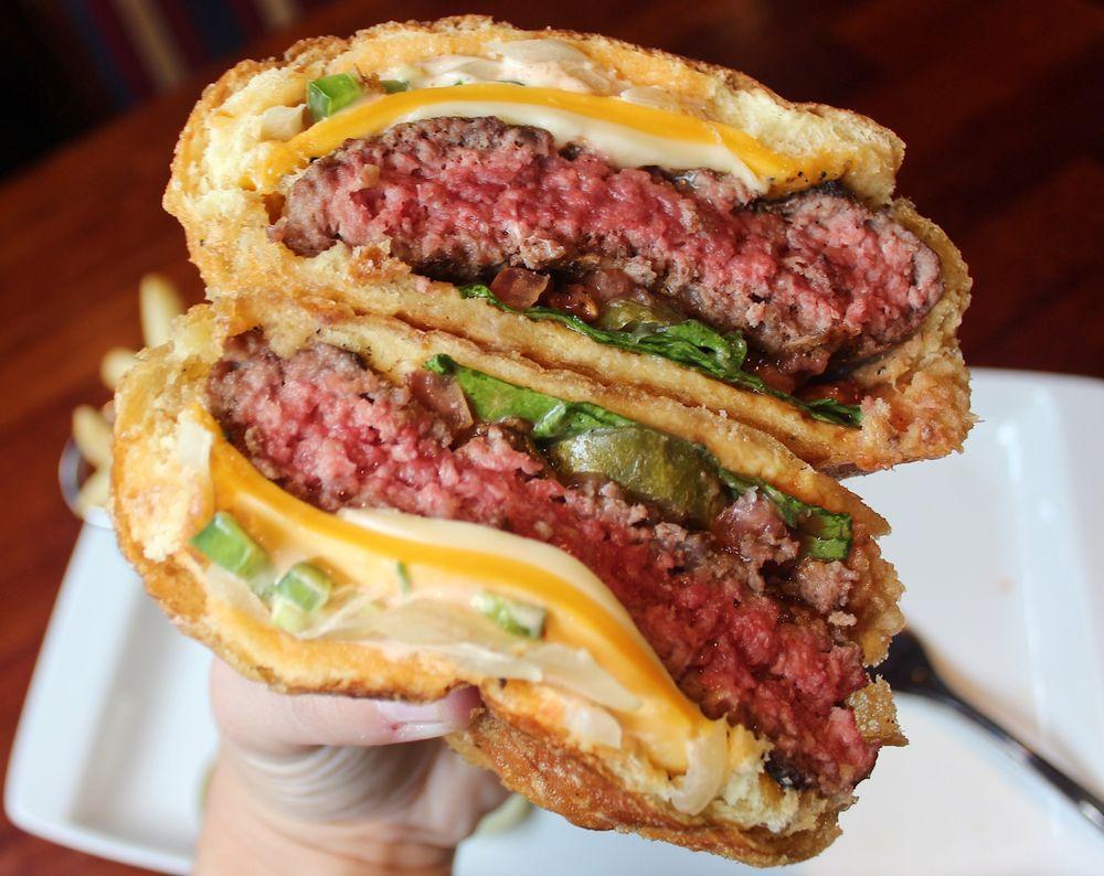 The Murder Burger · Served on a brioche roll with American and pepper jack cheese, sauteed onions, jalapenos, lettuce, tomato, housemade pickles, ketchup and Thousand Island dressing. Dipped in our Harp beer batter and deep-fried until golden and crispy.