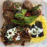 Dolmeh · Steamed stuffed grape leaves with tabouli and raisin, served over rice and topped with yogur...