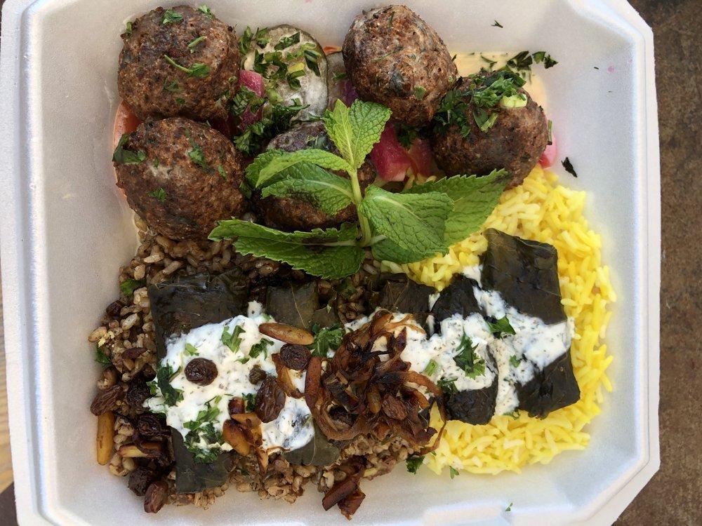 Dolmeh · Steamed stuffed grape leaves with tabouli and raisin, served over rice and topped with yogurt sauce.