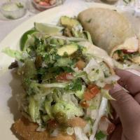 Tostada · Homemade Crispy tostada coated with refried beans and topped with lettuce avocado and Cotija...