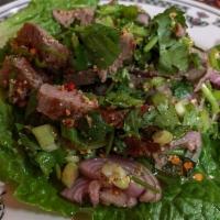 Nam Tok Salad · Grilled beef or pork shoulder, shallots, scallions, chiles, herbs and toasted rice powder.