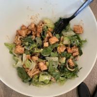 Tomahawk Chop Salad · Crisp romaine lettuce, fresh avocado, chopped bacon, black bean and corn salsa, and wonton n...