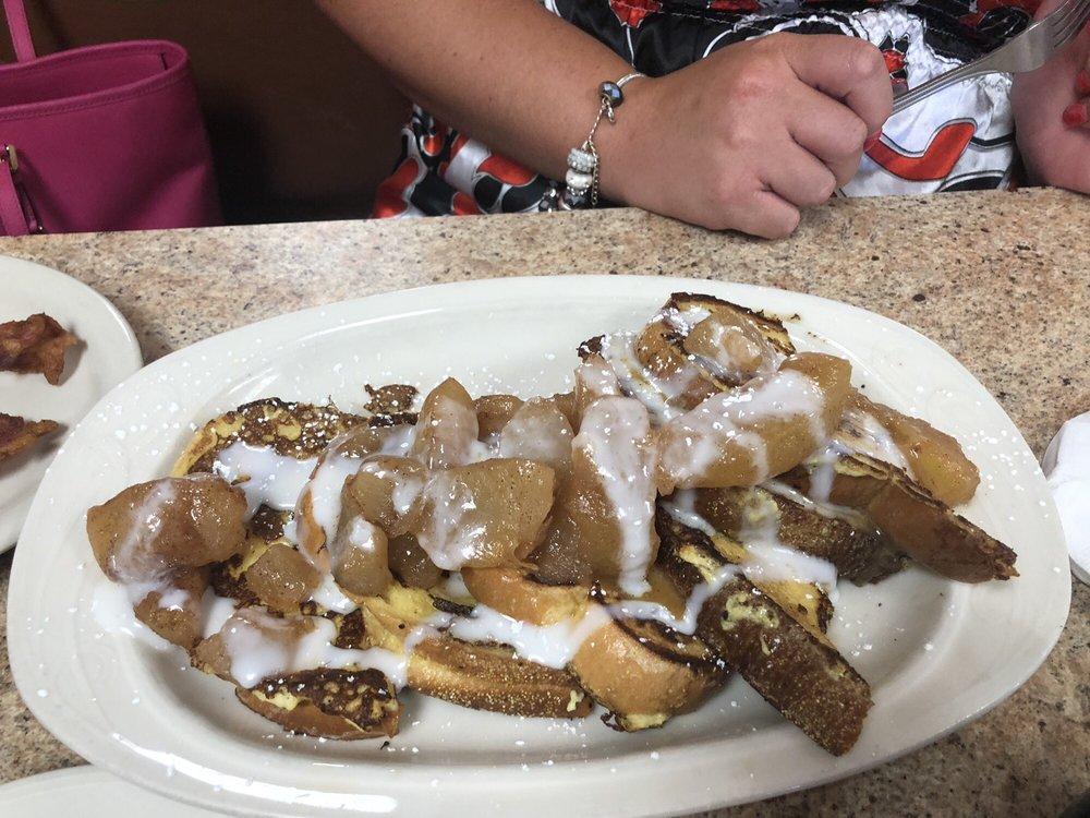 Apple French Toast · Fresh baked challah bread topped with warm apples and a vanilla cream cheese glazed finished with sprinkles and powdered sugar.