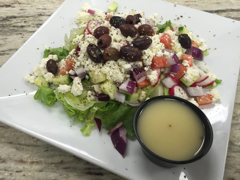 Greek Salad · Chopped salad topped with feta cheese and Kalamata olives served with house lemon herb vinaigrette on the side.