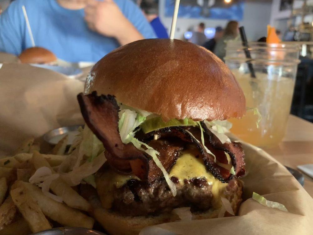 Backyard Burger · Sirloin/Brisket beef patty, tomato, grilled red onion, smoked bacon, sharp cheddar, lettuce, pickle and 1000 Island, house-made bun, served with hand-cut fries.