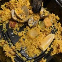Paella Valenciana · Traditional paella featuring chicken, calamari, chorizo, mussels, shrimp, and vegetables on ...