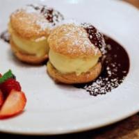 Profiteroles · Homemade vanilla ice cream in puff pastry shells served with chocolate sauce and berries.