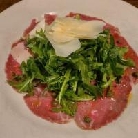 Carpaccio · Raw, thin beef tenderloin with rugola and capers in lemon dressing.