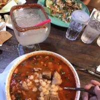 Pozole · Michoacan style red soup with pork and hominy garnished with onions, oregano, jalapeno, and ...