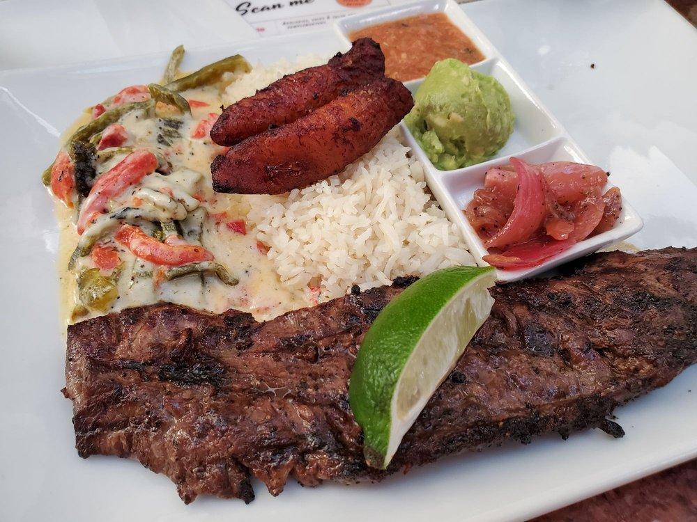 Carne Asada · Choice of lime-garlic marinated and grilled prime arrachera (skirt steak), served with garlic basmati rice, sweet plantains, black beans, duni onions, roasted poblano - red bell pepper cheese rajas, fire-roasted tomato salsa and mashed avocado. Bife de chorizo (strip loin) available for an additional charge. Make it gluten free (no rice and beans) upon request.