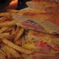Torta Cubana Sandwich · Grilled french baguette with sliced tomatoes, gruyere cheese, baby Swiss, honey ham, roasted...