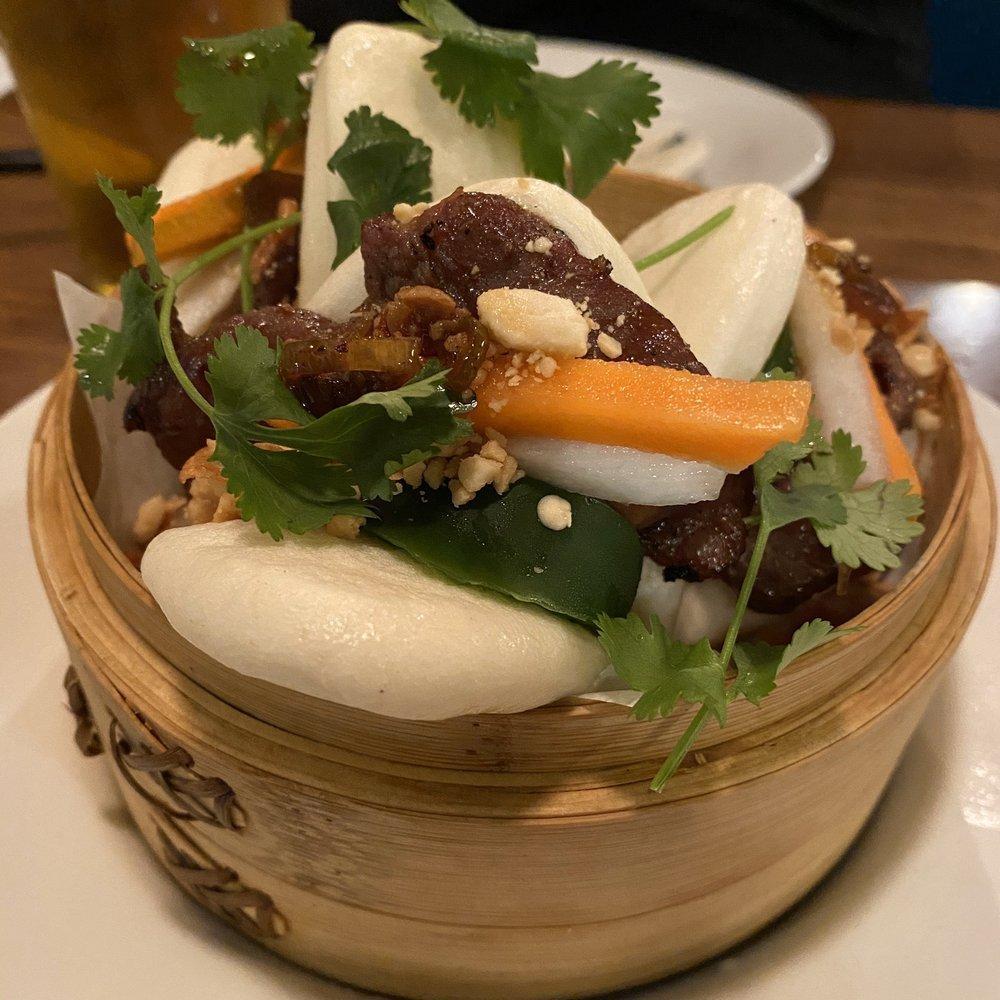 Grilled Pork Bao · Grilled lemongrass pork, cilantro, pickled vegetables, topped with crispy shallots and crushed peanuts and house special sauce.