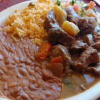 Carne Guisada · Stewed beef with vegetables, served with rice, beans, and pico de gallo.