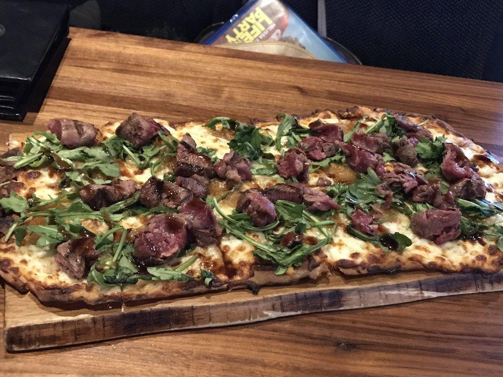 Prime Beef Flatbread · Prime beef steak sautéed with caramelized onions, mozzarella and bleu cheese, topped with arugula and balsamic
