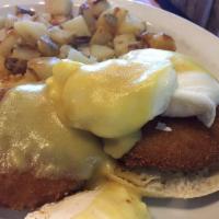 Crab Cake Benedict · Crab cakes on top of a split English muffin topped with three poached eggs and hollandaise s...