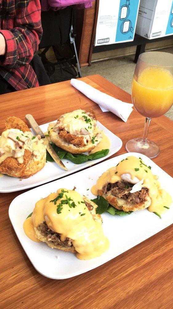 Eggs Cochon · Apple-braised pork debris served over a buttermilk biscuit, topped with two poached eggs and finished with hollandaise