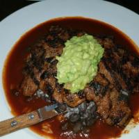 Carne Asada · Chargrilled skirt steak, served over black beans and rice, topped with guajillo sauce and gu...