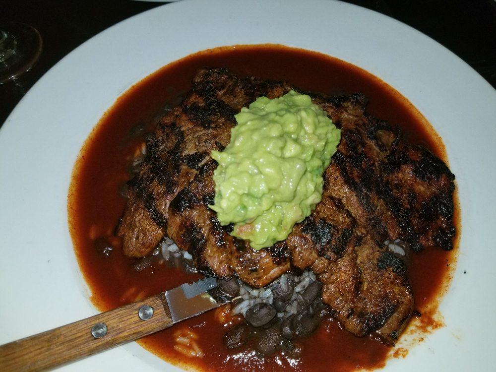 Carne Asada · Chargrilled skirt steak, served over black beans and rice, topped with guajillo sauce and guacamole.