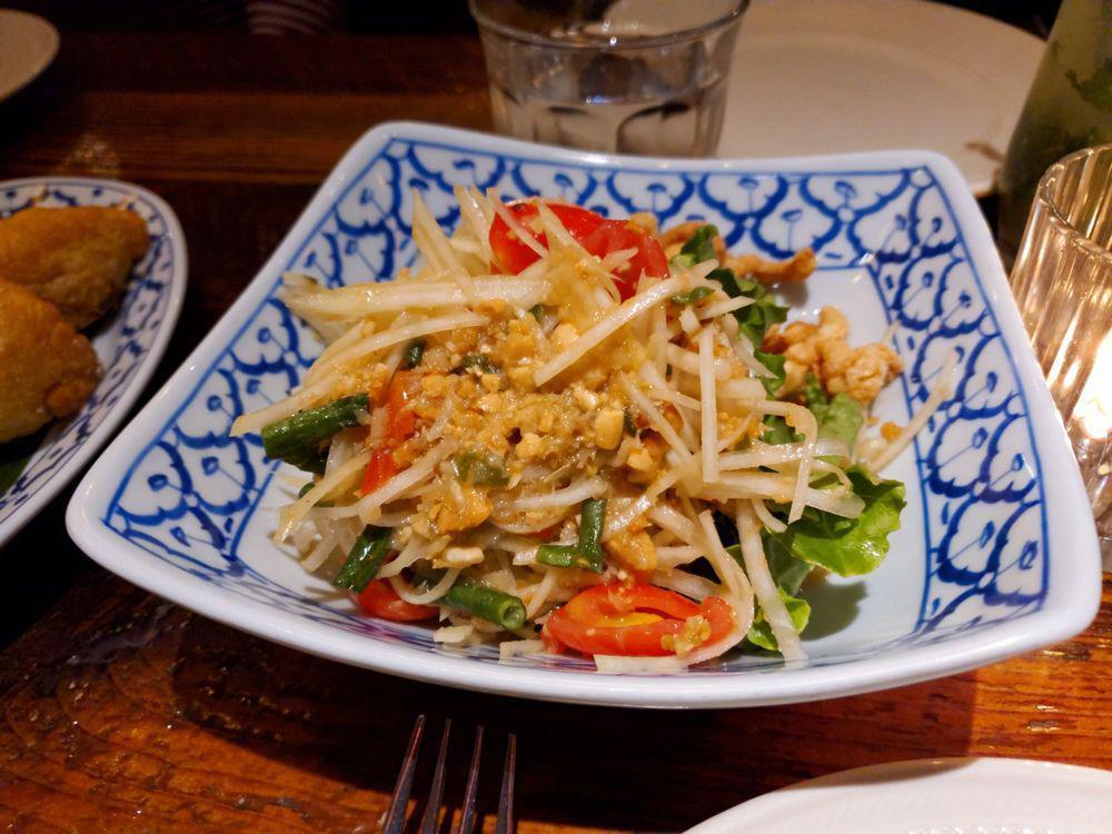 Papaya Salad · Shredded papaya, string beans, tomatoes and peanuts with Thai chili-lime dressing and topped with dried shrimp powder and crispy pork rinds. Spicy. Gluten free.